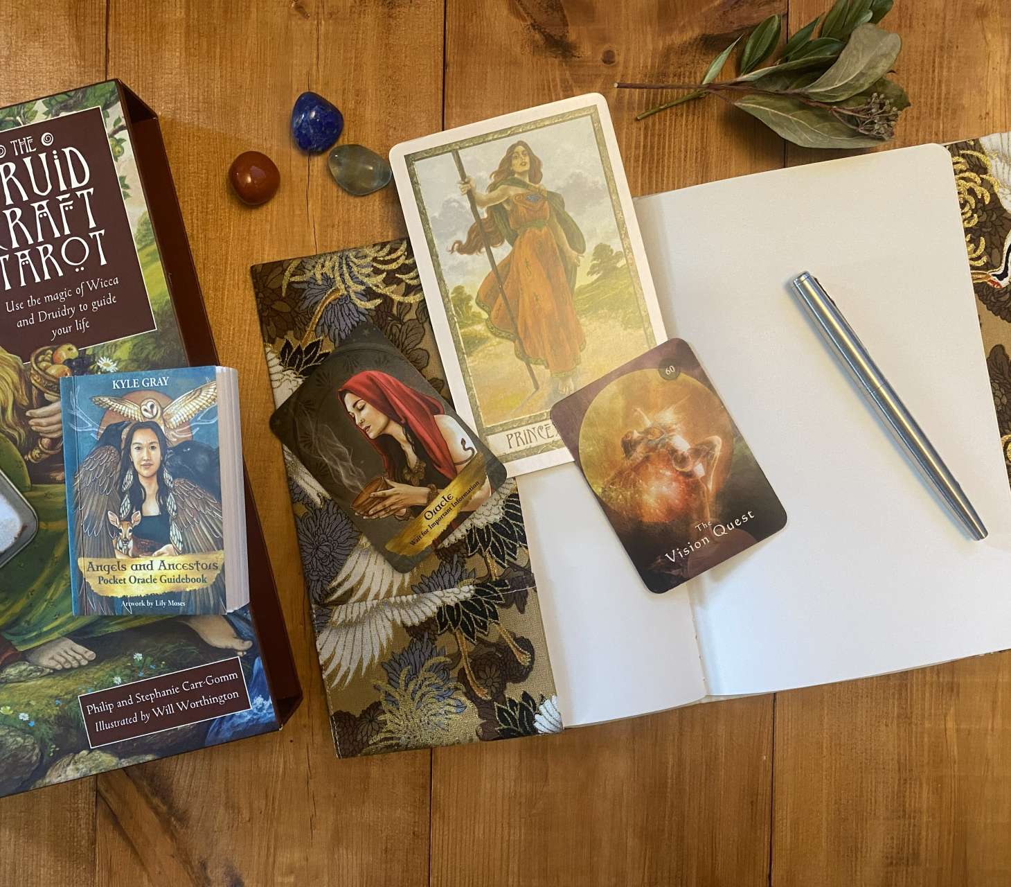 Tarot and oracle cards on a board with a notebook and pen